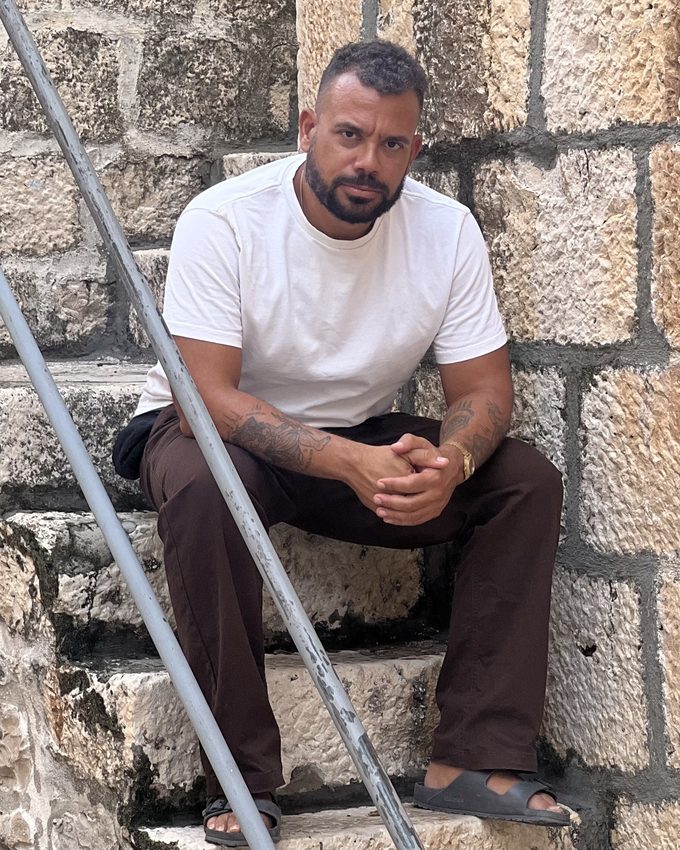 Chris seated on stone steps against a carved stone wall